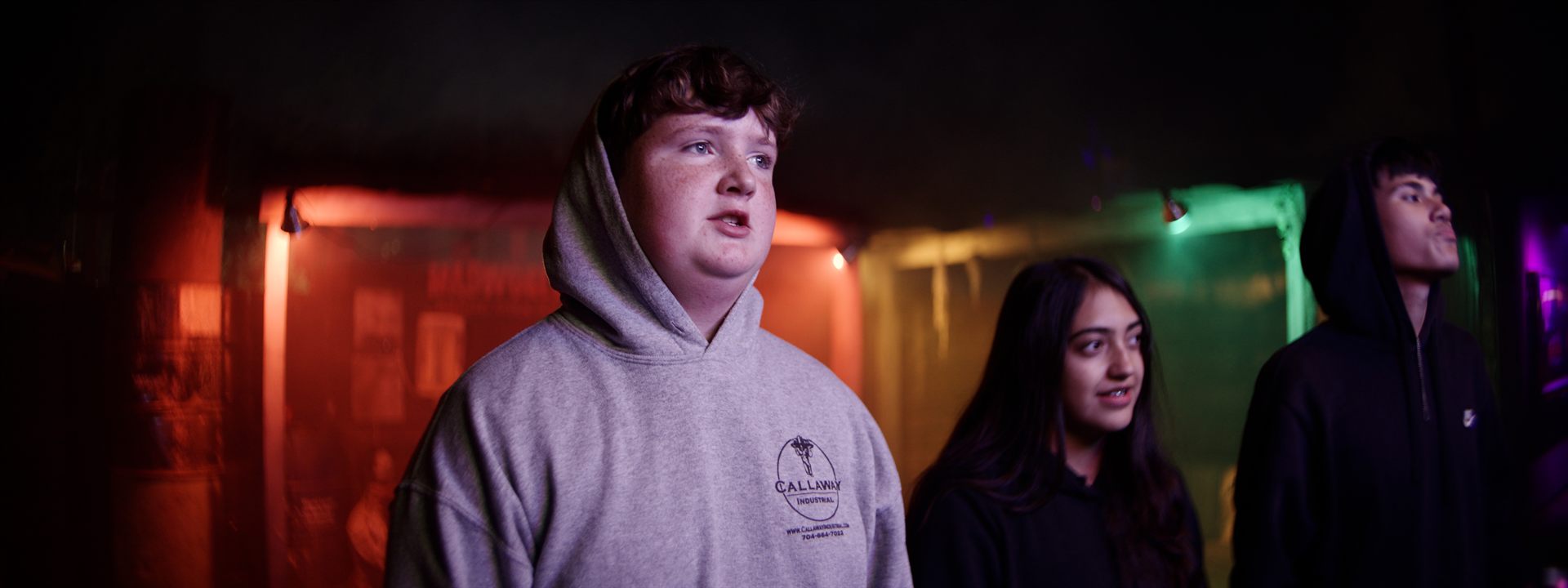 A wide environmental shot from the Madworld grounds — atmospheric night, haunted attraction lighting